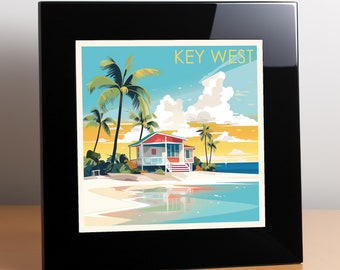 May include: A square framed print featuring a stylized illustration of a Key West beach scene with a red and white house, tall palm trees, and a calm blue ocean under a bright sky. The text KEY WEST is printed in yellow at the top right corner.