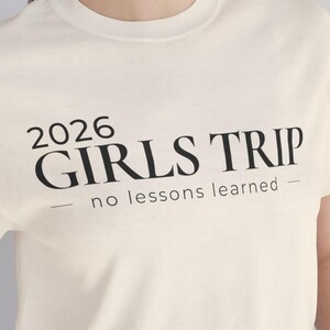 May include: Cream-colored t-shirt with the text "2026 GIRLS TRIP - no lessons learned" in black. The shirt also includes file type options: SVG, PNG, PDF, EPS, and DXF, with "Instant Download" text.