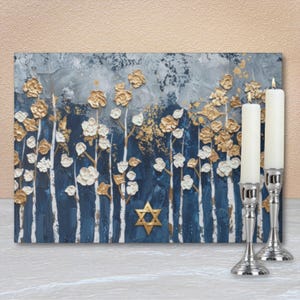 May include: An abstract painting with a textured finish, depicting a forest scene in shades of blue, white, and gold. A Star of David is centered on the painting. Two white candles stand in silver candlesticks.