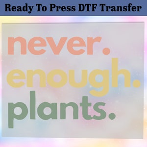 May include: Ready to Press DTF Transfer with the text "never. enough. plants." in pink, yellow, and green on a white background with a blurred rainbow effect.