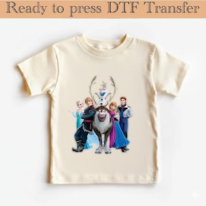 May include: A cream-coloured t-shirt with a graphic of characters from the animated film "Frozen", including Elsa, Anna, Kristoff, Olaf, and Sven. The text "Ready to press DTF Transfer" is at the top.