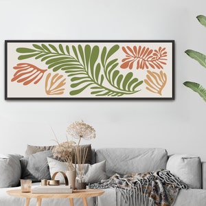 May include: A framed print with a minimalist design featuring abstract green and orange leaf shapes on a cream background.