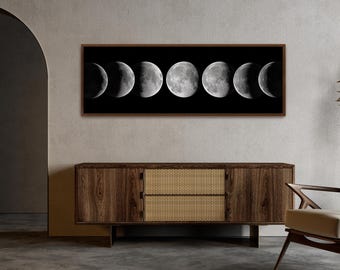 May include: A black and white photograph of the moon in different phases. The image is framed in a dark brown frame and is hanging on a wall above a wooden cabinet.