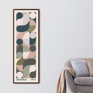 May include: A framed print with a geometric design in shades of pink, green, and blue. The print features a repeating pattern of circles, semi-circles, and squares. The text "BAUHAUS 1919" is printed at the bottom of the print.