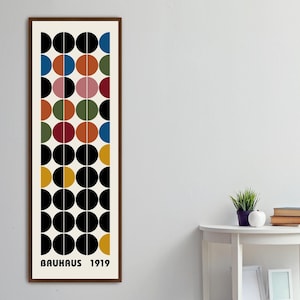 May include: A framed print with a geometric design of black, white, yellow, red, blue, green, and brown circles. The print has the text "BAUHAUS 1919" at the bottom.
