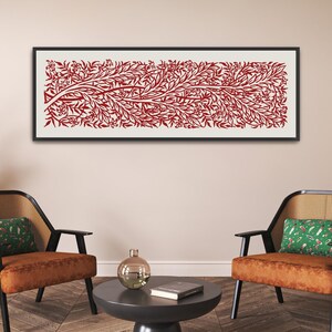 May include: Two brown chairs with green patterned cushions and black frames sit in front of a white wall with a framed red and white abstract art print hanging above them.