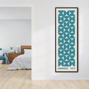 May include: A framed print with a geometric pattern of teal blue circles and white triangles on a cream background. The print has the text "Bauhaus 1919" at the bottom.
