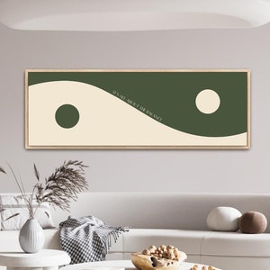 May include: A white sofa with two throw pillows sits in a living room with a white coffee table and two white side tables. A green and white abstract art print hangs on the wall above the sofa. The print features two circles and the text "We all grow in our own time".