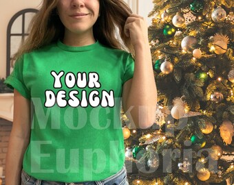 May include: A woman wearing a green t-shirt with the text "YOUR DESIGN" in white. She is standing in front of a decorated Christmas tree.