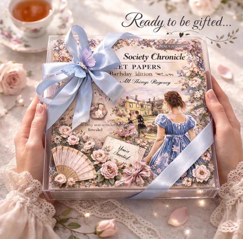 Luxury Regency inspired spa gift box held in hands, beautifully wrapped with blue ribbon and floral Society Chronicle design, ready to be gifted pamper set for her with romantic vintage aesthetic.