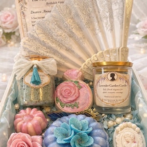 Luxury self care spa gift set with candle, bath salts, bath bombs and handmade soaps arranged in a pastel blue gift box with romantic vintage aesthetic.