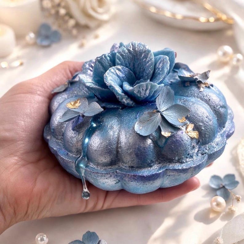 Large handmade blue floral bath bomb held in hand, decorative bath bomb from a luxury spa gift box.