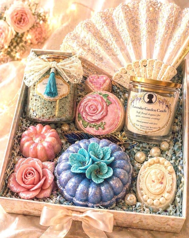 Luxury spa gift box with handmade soaps, bath bombs, lavender bath salts and scented candle, beautifully arranged in an elegant open box with decorative fan and floral details, perfect gift for her