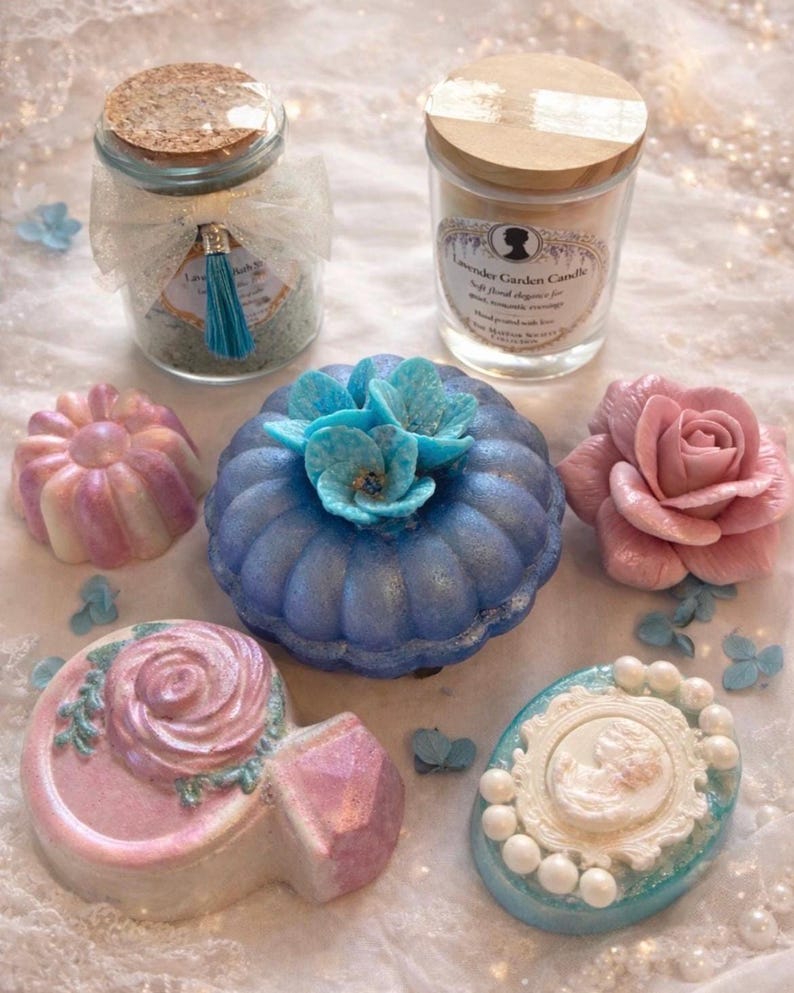 Luxury spa gift set items including bath salts, candle, bath bombs and handmade soaps arranged on lace with pearls.