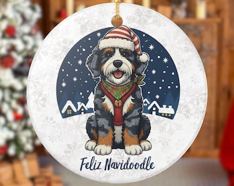 May include: Round Christmas ornament featuring a Bernedoodle dog wearing a Santa hat and a red and green scarf. The background shows a snowy night scene with houses and snowflakes. The text "Feliz Navidoodle" is at the bottom.