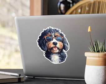 May include: A sticker featuring a cartoon dog with black, brown, and white fur wearing sunglasses with orange frames. The dog has its tongue sticking out. The sticker is on a laptop.