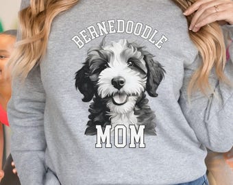 May include: A gray sweatshirt featuring a black and white Bernedoodle dog graphic with the text "BERNEDOODLE MOM" in white block letters. The dog illustration has a smiling expression.