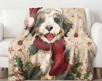 May include: A cozy throw blanket featuring a smiling dog wearing a Santa hat and a red scarf. The blanket has a beige background with Christmas-themed illustrations, including stars, ornaments, and holly.