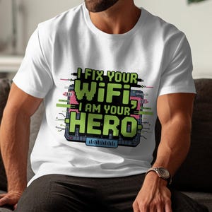 Può includere: T-shirt bianco con grafica pixelata verde e rosa: "I FIX YOUR WIFI I AM YOUR HERO". Il design include elementi di circuiti stampati. Una maglietta casual per tutti i giorni.