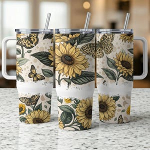 May include: Three stainless steel tumblers with a white background and a pattern of sunflowers and butterflies. The tumblers have a lid and a handle.