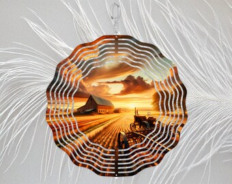 May include: A circular metal wind spinner with a wavy, scalloped edge featuring a printed sunset scene of a farm field, a barn, and a tractor. The design is centered on a metallic disc with a small hanging loop at the top for suspension.