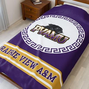 May include: Purple and gold fleece blanket with a white circle featuring a black panther and the text "PVAMU" in purple and gold. The text "Prairie View A&M" is written in gold on a purple background.