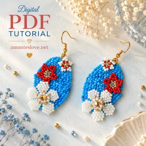 Puede incluir: Un par de pendientes de cuentas en forma de lágrima con un fondo azul brillante y motivos florales rojos y blancos. Las flores están adornadas con pequeñas cuentas doradas en el centro. Los pendientes cuelgan de ganchos de metal dorado.