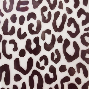 Pode incluir: Um fundo branco com um padrão de estampa de leopardo marrom. A estampa é composta por manchas e redemoinhos de diferentes tamanhos.