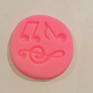May include: Pink silicone mould with three musical note shapes. The mould features a treble clef and two quaver notes.