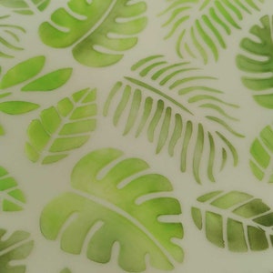 May include: A white background with a repeating pattern of green watercolour leaves. The leaves are in various shapes and sizes, including palm leaves, monstera leaves, and fern leaves.