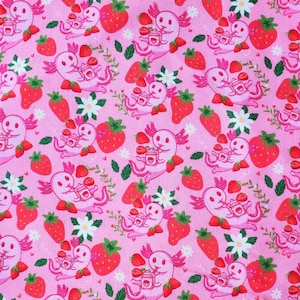 Puede incluir: Tela rosa con un patrón repetido de ajolotes rosas bebiendo de una taza y fresas rojas. Los ajolotes están rodeados de hojas verdes y flores blancas.