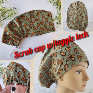 May include: A scrub cap with a toggle lock, featuring a pattern of orange butterflies on a green background. The cap is designed for medical professionals and is shown in multiple views.
