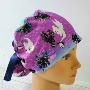 May include: Purple scrub hat with a tie, featuring a repeating pattern of black and white dragons on a purple background with white stars.