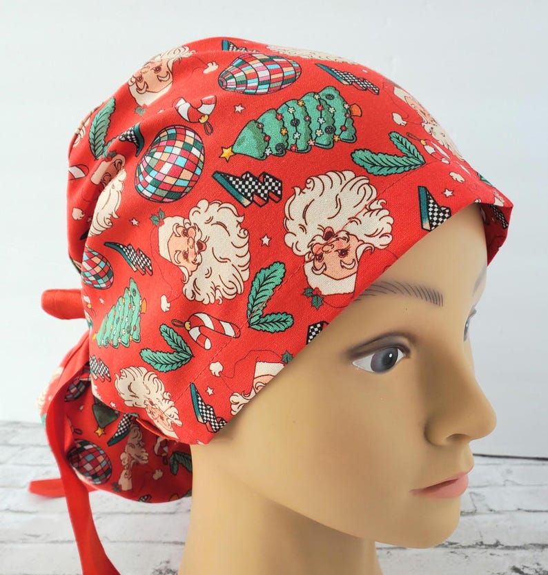 May include: Red surgical scrub hat with a Christmas themed print featuring Santa Claus, Christmas trees, candy canes, and ornaments.