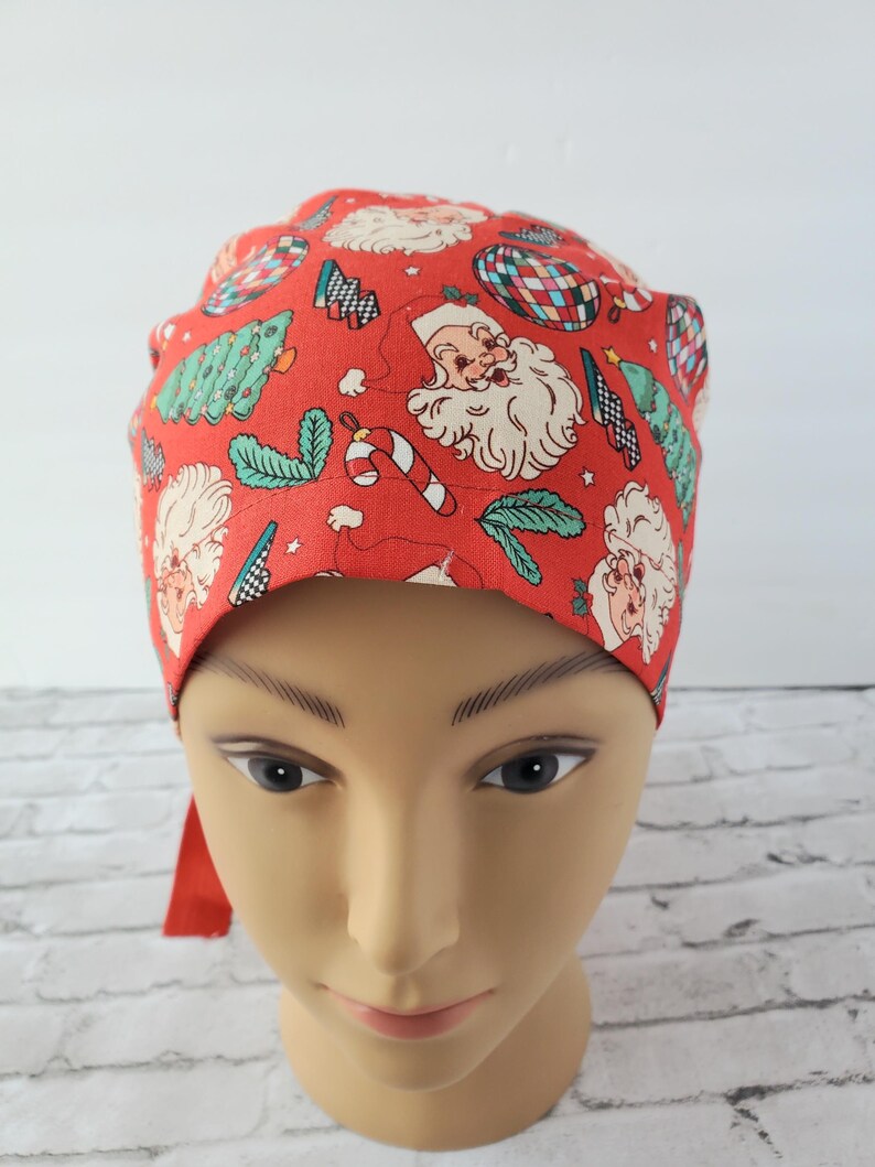 May include: Red scrub hat with a Christmas print featuring Santa Claus, candy canes, Christmas trees, and ornaments.
