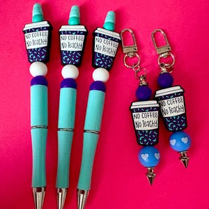 May include: Turquoise pens and keychains with coffee cup charms. The charms have the text "NO COFFEE No Teachy" on a black and purple leopard print background. The pens have white and purple beads.