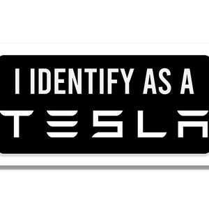 以下が含まれることがあります： 黒い背景と白い文字の長方形のステッカー。「I IDENTIFY AS A」の文字が白のテスラロゴの上にあります。ステッカーには白い縁があります。