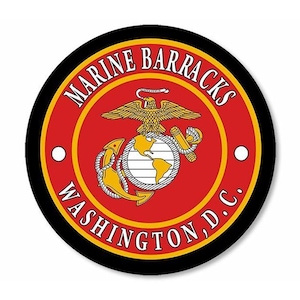 May include: Circular emblem featuring the words "MARINE BARRACKS WASHINGTON, D.C." in white text. The emblem has a red background with a gold eagle, globe, and anchor in the center. A black border surrounds the emblem.