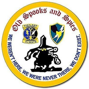 May include: A yellow circle with the text "Old Spooks and Spies" around the edge. Inside the circle is a black silhouette of a person running with a gun. There are two patches above the person, one blue with the text "Vigilant Always" and the other green with a lightning bolt. The text "WE WEREN'T HERE, WE WERE NEVER THERE, WE DON'T EXIST." is written around the bottom of the circle.