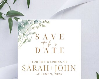 Può includere: Carta di salvataggio della data con un design di eucalipto ad acquerello. La carta è bianca con testo dorato che recita "Save the Date" per il matrimonio di Sarah + John il 9 agosto 2025. La carta include anche la posizione del matrimonio, The Anywhere Hotel, 123 Anywhere St., Any City, e il testo "invito formale a seguire".