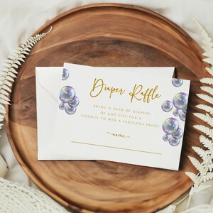 May include: White card with gold text that reads "Diaper Raffle" and "Bring a pack of diapers of any size for a chance to win a fabulous prize!" The card is decorated with iridescent blue and purple bubbles.