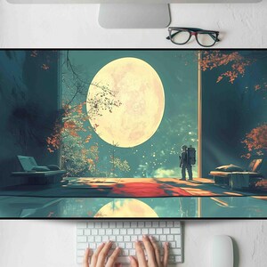 May include: A large, rectangular desk mat featuring a surreal landscape with an astronaut gazing at a giant moon. The scene includes a red carpet, trees with orange leaves, and a reflective surface. The color palette is dominated by blues, greens, and oranges.