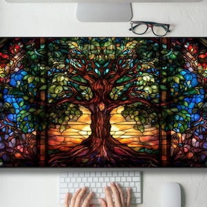 May include: A stained glass window depicting a large tree with a sunset behind it. The tree has a thick trunk and many branches with green leaves. The sunset is a vibrant orange and yellow.