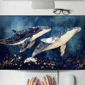 May include: A blue and gold whale-themed desk mat featuring two whales swimming in a dark blue ocean. The whales have a detailed design with gold accents. The mat is rectangular and sits on a white desk with a keyboard and mouse.