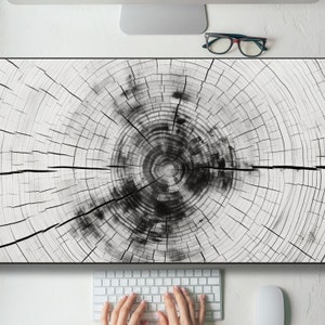 May include: A close-up of a wood grain pattern with concentric circles, resembling a tree trunk cross-section. The wood grain is light brown with darker brown rings.