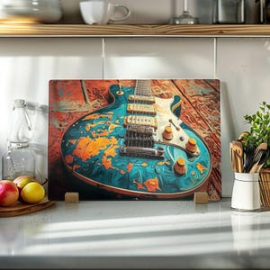 Peut inclure: Une planche à découper rectangulaire en verre présentant une illustration artistique vibrante d'une guitare électrique. Le corps de la guitare affiche un motif tourbillonnant de teintes bleu sarcelle, bleu et orange sur un fond en bois texturé.