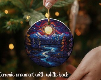May include: Ceramic ornament featuring a stained glass style design of a moonlit forest scene with a river winding through the trees. The ornament has a white background.