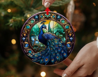 Könnte beinhalten: Runder Weihnachtsschmuck mit einem Pfauen-Design. Der Pfau ist in Blau-, Grün- und Goldtönen mit einem Glasmalerei-Effekt dargestellt. Der Schmuck hat ein rotes Band zum Aufhängen und wird von einer Person gehalten.