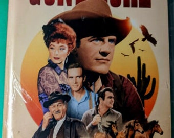 May include: A DVD cover for Gunsmoke, a Western TV series. The cover features a group of actors, including James Arness, who played Matt Dillon, and a title card that reads "Gunsmoke Seasons 1-9".
