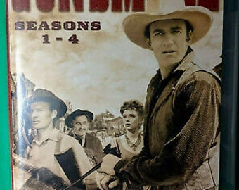 May include: A DVD box set featuring the TV show Gunsmoke, with a photo of the main character on a horse. The box set includes seasons 1-4.